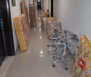 Wrapped mattresses and office chairs lined up in a hallway during a move